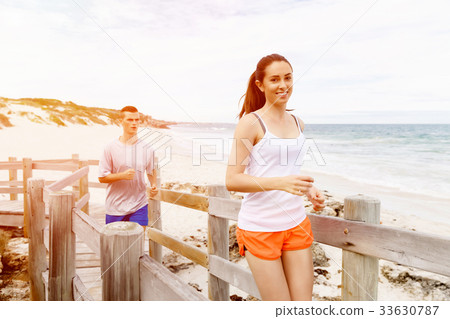 Runners. Young couple running on beach 33630787