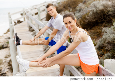 Runners. Young couple exercising and stertching on beach 33631262