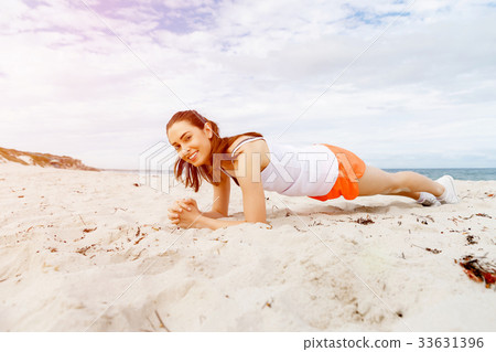 Young woman training on beach outside Young woman training on beach outside 33631396