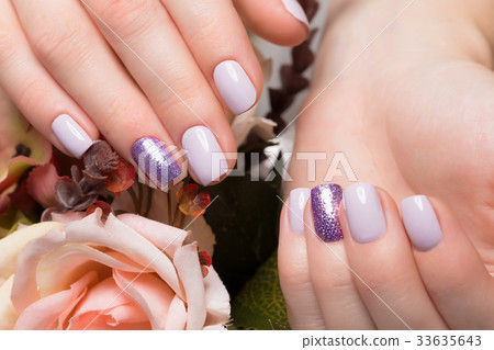 Purple neat manicure on female hands on flowers 33635643