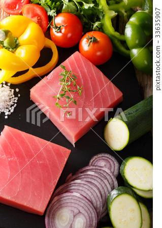 Raw fillet of tuna surrounded by fresh vegetables Raw fillet of tuna surrounded by fresh vegetables 33635907
