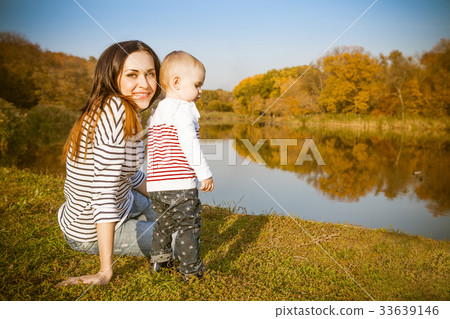 Smiling mother and baby on autumn lake Smiling mother and baby on autumn lake 33639146