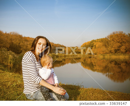 Smiling mother and baby on autumn lake Smiling mother and baby on autumn lake 33639147