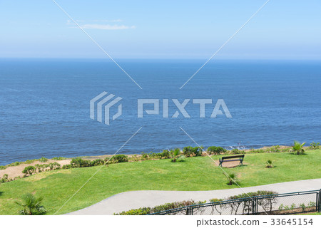 empty bench facing towards the ocean coast empty bench facing towards the ocean coast 33645154