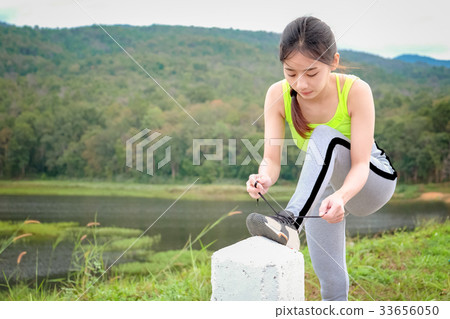 Young woman tying her sports shoes on exercising  33656050