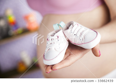 Pregnant woman holding a pair of tiny shoes Pregnant woman holding a pair of tiny shoes 33662439