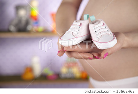 Pregnant woman holding a pair of tiny shoes Pregnant woman holding a pair of tiny shoes 33662462