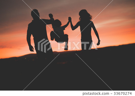 Mother and Father swinging son up in the air at Mother and Father swinging son up in the air at 33670274