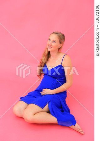 Blonde pregnant woman @ studio shot looking up wearing a blue dress Blonde pregnant woman @ studio shot looking up wearing a blue dress 33672106