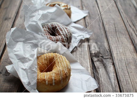 Three fluffy donuts in wrappers arranged in a row 33673875