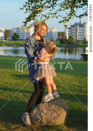 Little girl with mother on stone in sunset Little girl with mother on stone in sunset 33675843