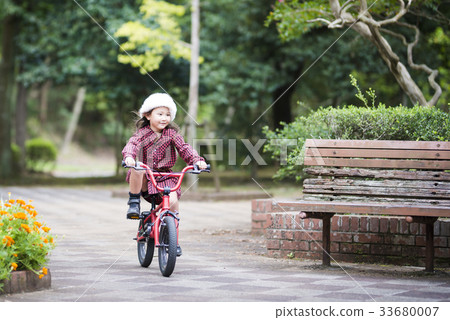 A girl riding a red bicycle 33680007