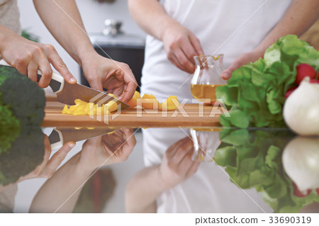 Close-up of four human hands are cooking in a 33690319