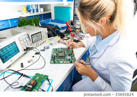 Female electronic engineer testing motherboard Female electronic engineer testing motherboard 33691624