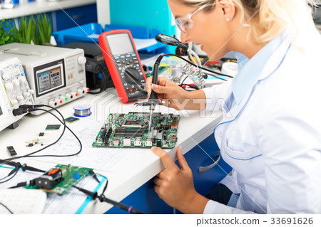 Female electronic engineer soldering motherboard 33691626