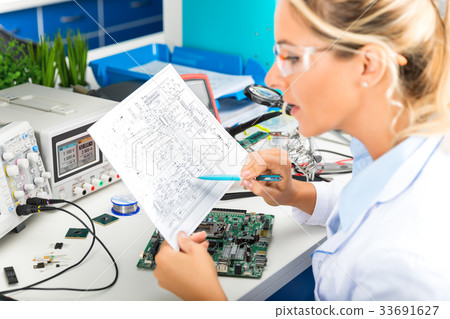 Female electronic engineer checking electronics Female electronic engineer checking electronics 33691627