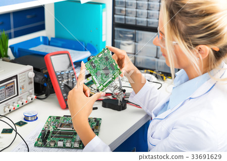 Female electronic engineer checking circuit board Female electronic engineer checking circuit board 33691629
