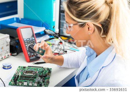 Female electronic engineer checking CPU microchip 33691631