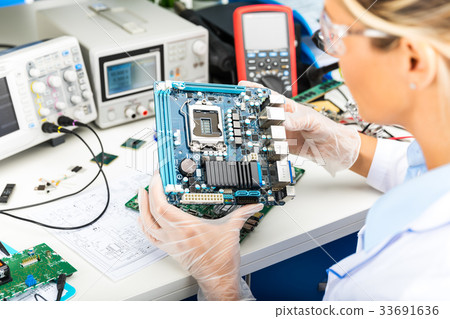Female electronic engineer examining motherboard Female electronic engineer examining motherboard 33691636