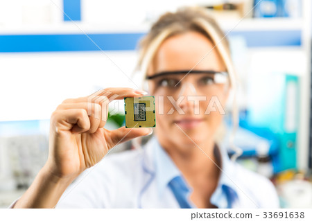 Young female electronic engineer holding CPU chip 33691638