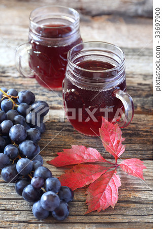Glasses of grape juice, black grapes and leaves Glasses of grape juice, black grapes and leaves 33697900