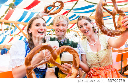 Friends with giant pretzels in Bavarian beer tent 33700759