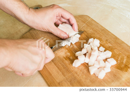 a man cuts raw pork fat into pieces 33700944