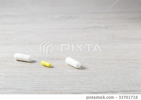 Three white and yellow medicine capsules Three white and yellow medicine capsules 33701718