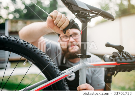 Bicycle mechanic adjusts with tools bike seat Bicycle mechanic adjusts with tools bike seat 33701733