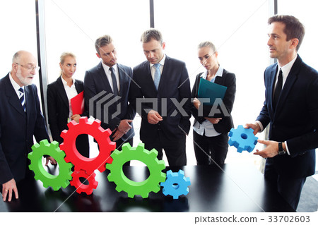 Business people assembling cogwheels Business people assembling cogwheels 33702603
