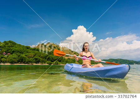 Young woman paddling during vacation in an idyllic 33702764