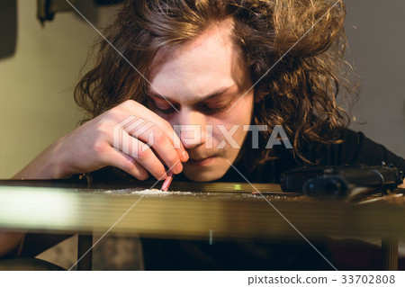 Drug addicted teenage boy holding a rolled bill 33702808
