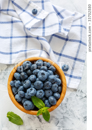 Blueberries and mint leaves in a wooden bowl. 33702880