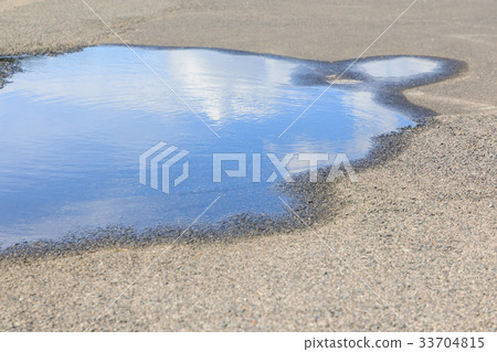 A puddle reflecting the blue sky-asphalt after the rain 33704815