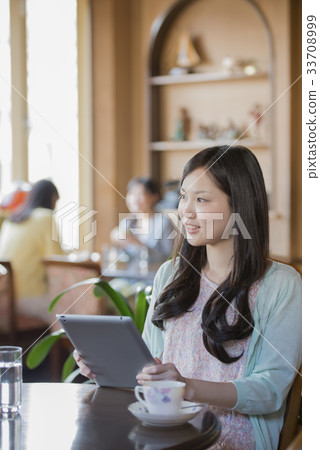 A woman holding a tablet PC and smiling A woman holding a tablet PC and smiling 33708999