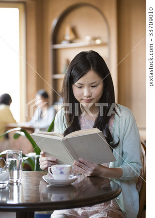 A woman reading a book at a cafe A woman reading a book at a cafe 33709010