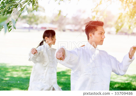 People practicing thai chi in park People practicing thai chi in park 33709486