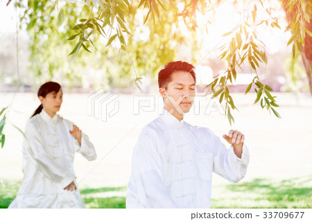 People practicing thai chi in park People practicing thai chi in park 33709677