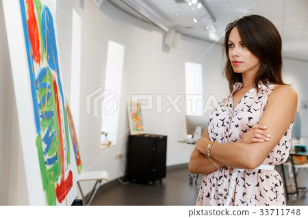 Young caucasian woman standing in art gallery front of paintings 33711748