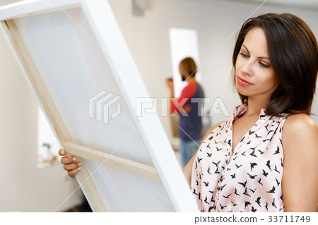 Young caucasian woman standing in art gallery front of paintings 33711749