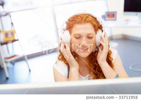 Young woman with headphones working in office Young woman with headphones working in office 33711958