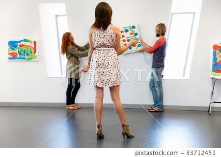 Young artists in gallery hanging painting on walls Young artists in gallery hanging painting on walls 33712451