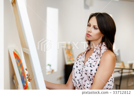 Young caucasian woman standing in art gallery front of paintings Young caucasian woman standing in art gallery front of paintings 33712812