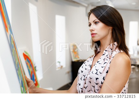 Young caucasian woman standing in art gallery front of paintings 33712815