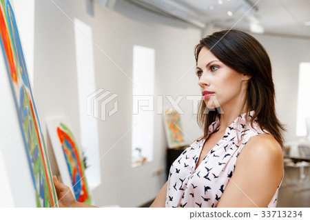 Young caucasian woman standing in art gallery front of paintings 33713234