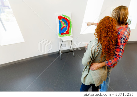 Young caucasian couple standing in a gallery and contemplating artwork 33713255