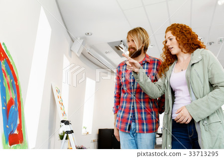 Young caucasian couple standing in a gallery and contemplating artwork 33713295
