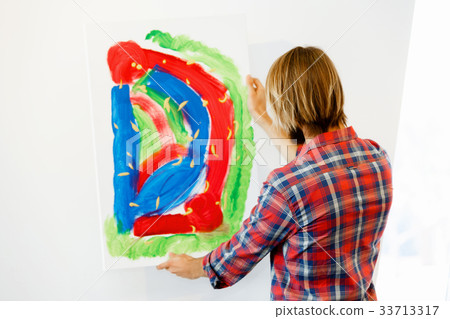 Young male artist standing with a picture 33713317
