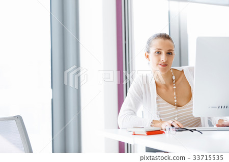 Attractive office worker sitting at desk Attractive office worker sitting at desk 33715535