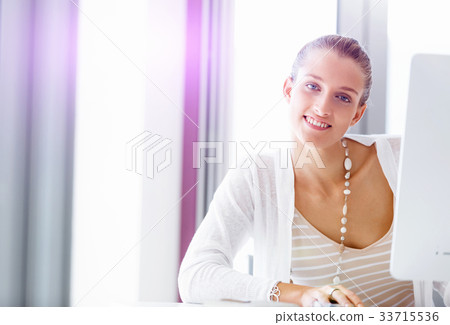 Attractive office worker sitting at desk 33715536